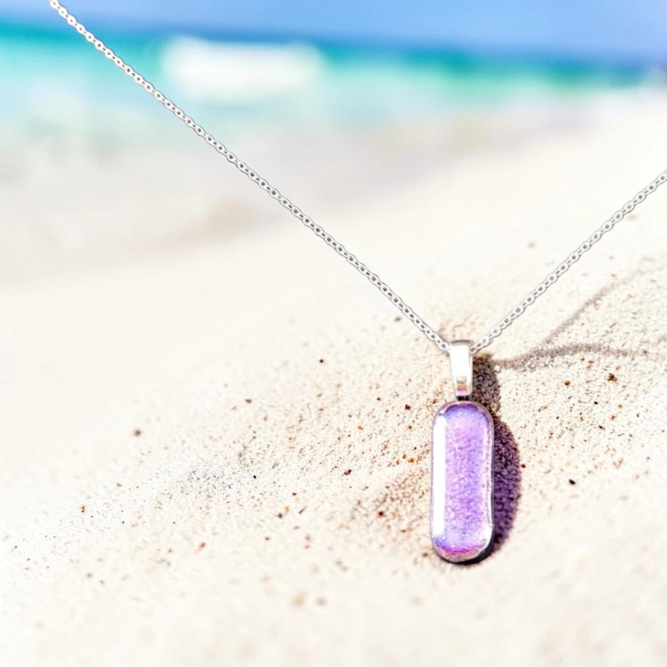 Découvrez ce pendentif verre dichroïque rose fait main France. Dans notre atelier français, nous façonnons chaque pièce en verre dichroïque rose fuchsia aux éclats lumineux par technique fusing. Ses reflets roses et violets vibrants créent un bijou unique, fin et élégant. Dimensions : 3 cm x 1 cm. Chaîne plaquée argent S925 46 cm incluse. Livré dans son écrin cadeau.